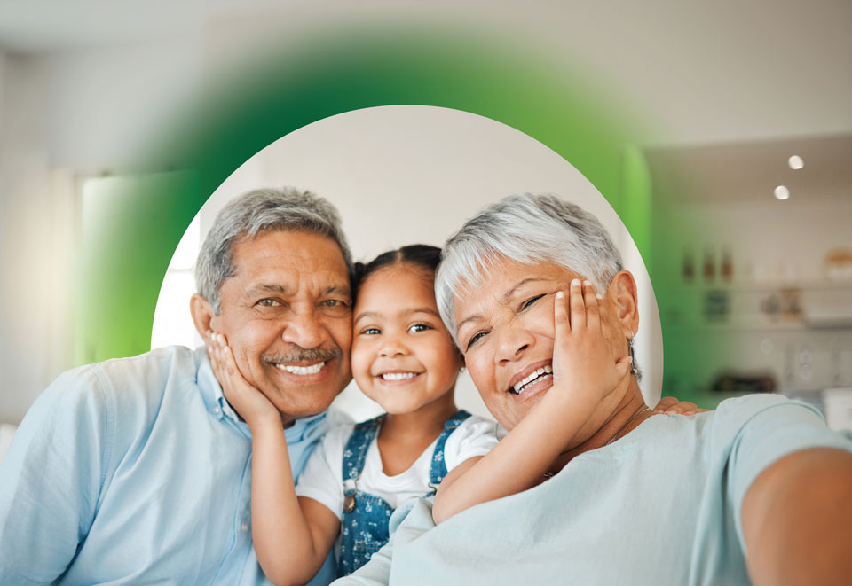 Smiling child holds the faces of two older people while sitting between them.