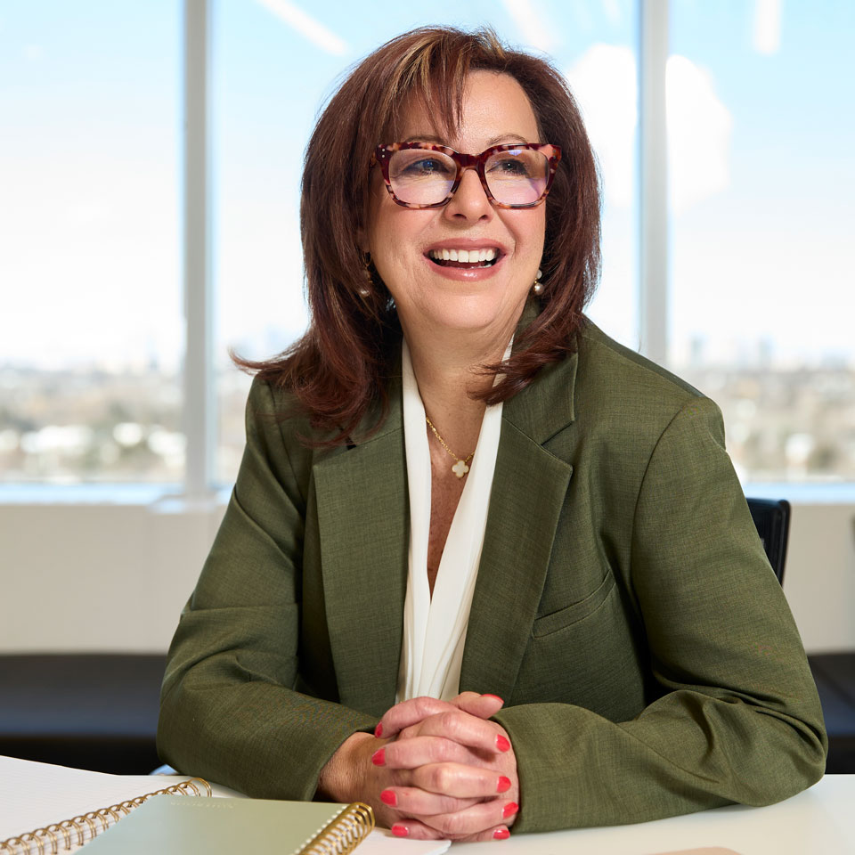 Securian Canada employee in a green blazer smiles while seated in a conference room.