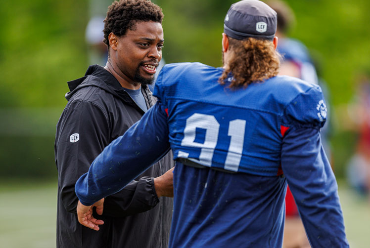 Football coach offers advice to a player during a practice.