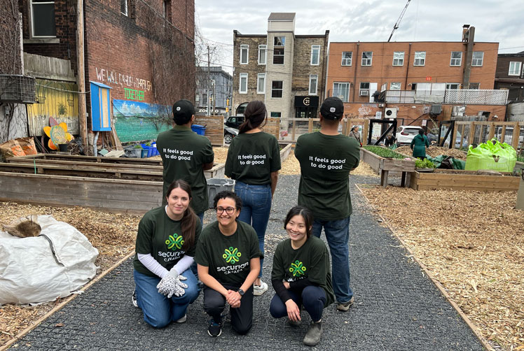 Group of Securian Canada employees in branded t-shirts volunteer at a community gardening event.