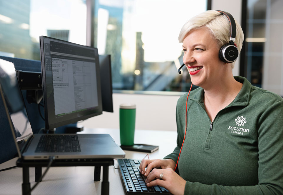 Securian Canada call centre rep wearing a headset smiles while helping a customer.