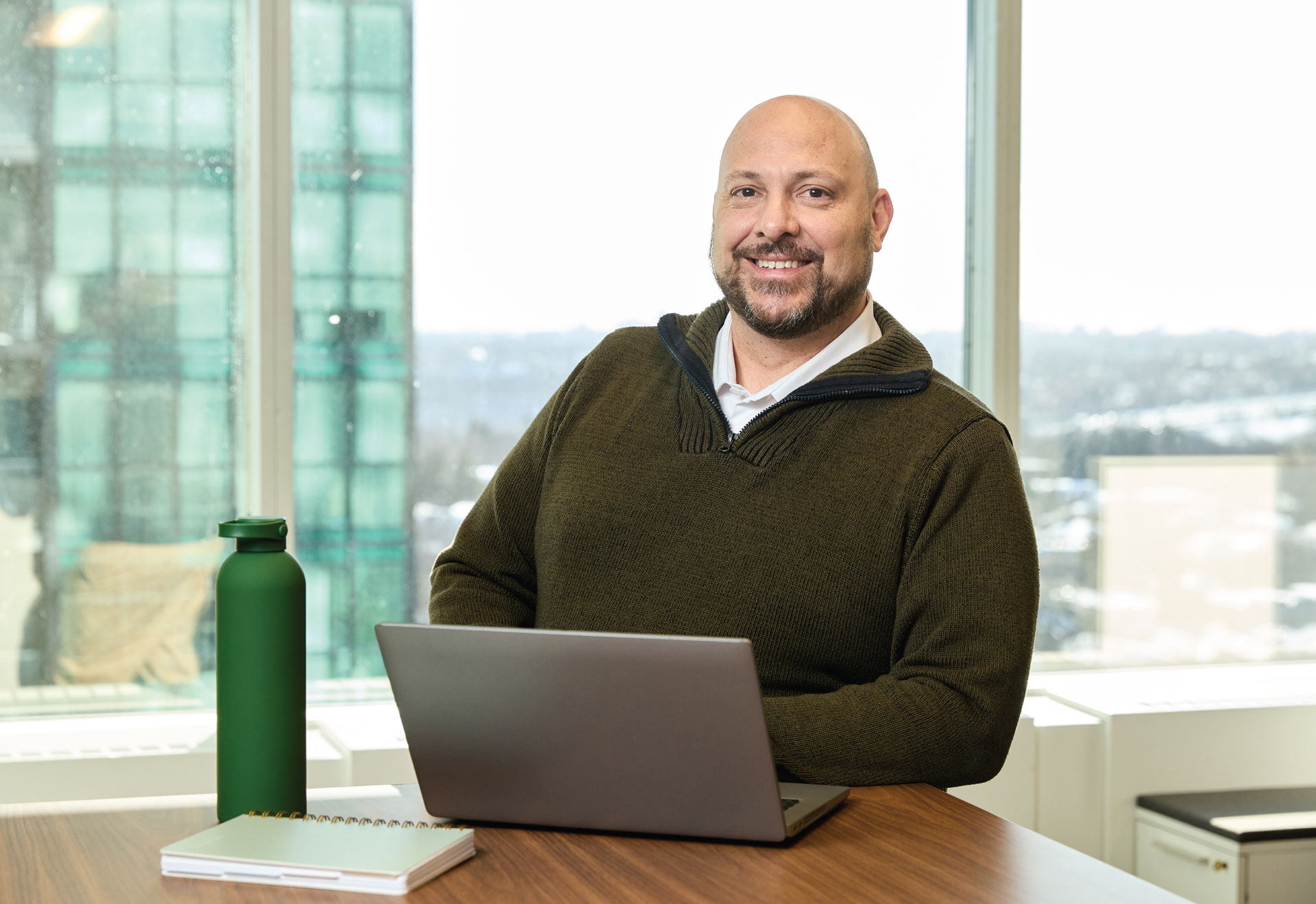 Securian Canada employee smiles in an office while working on a laptop.