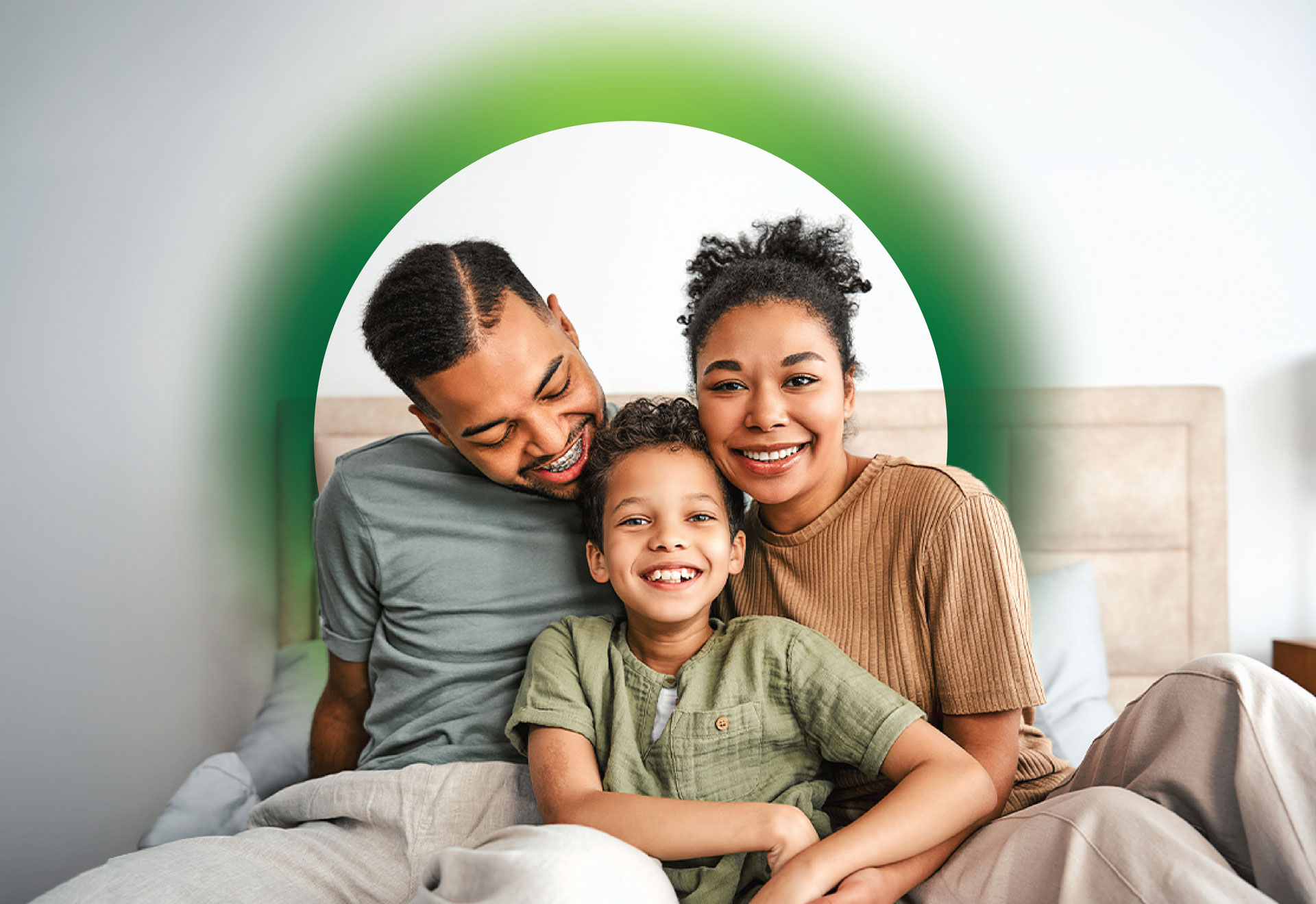 Two adults and young child sit together on a couch, smiling.