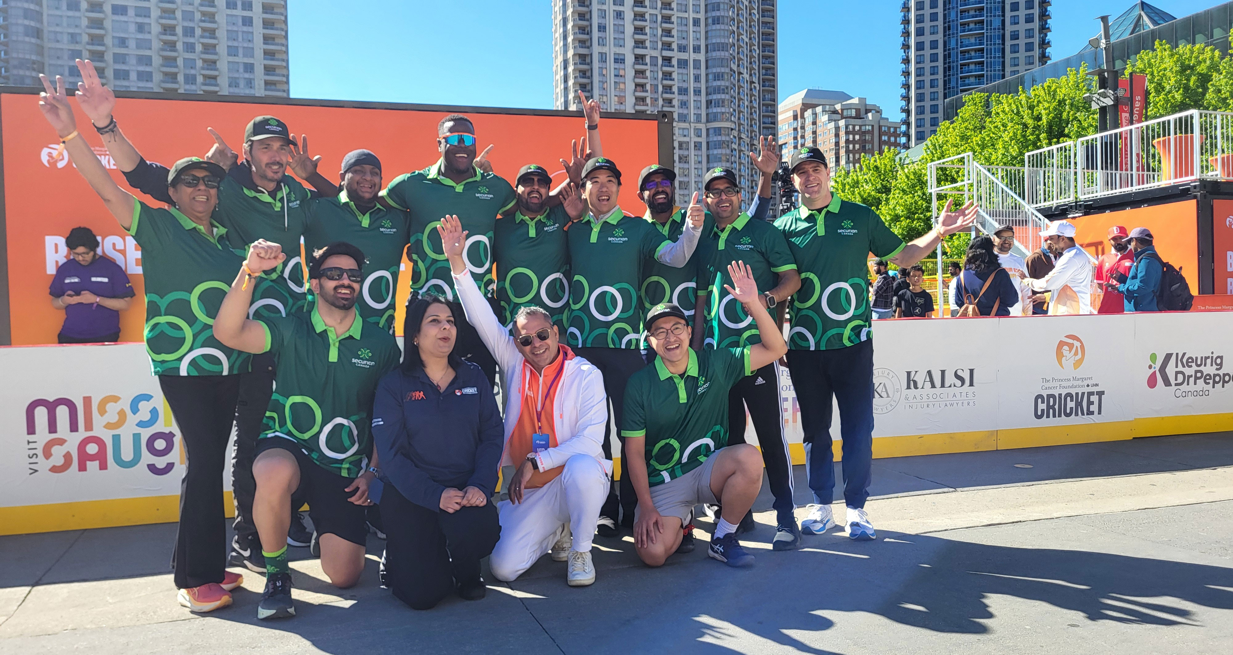 Group of Securian Canada employees wearing branded uniforms cheer at a cricket tournament.