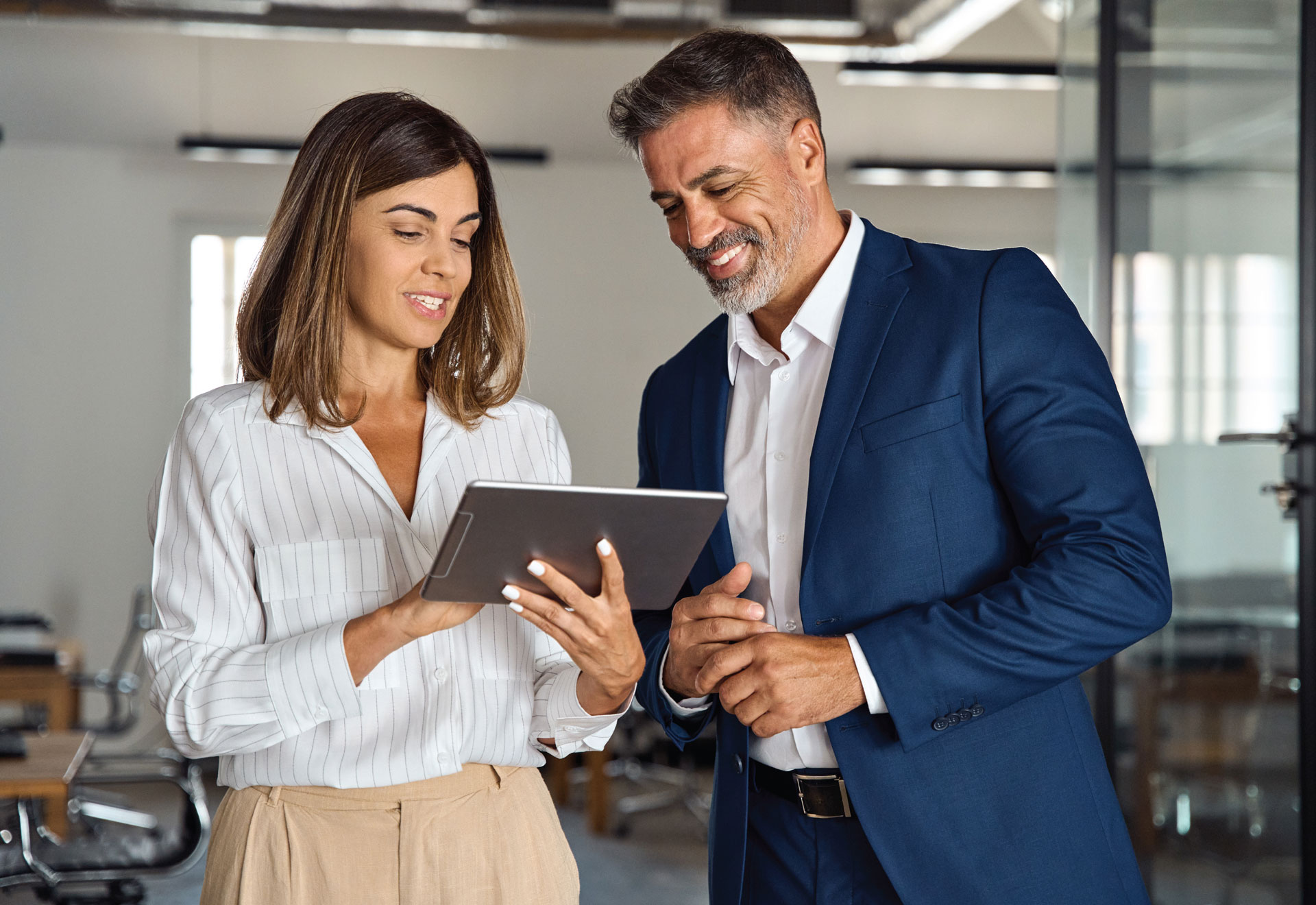 Deux professionnels consultent une tablette dans un bureau.