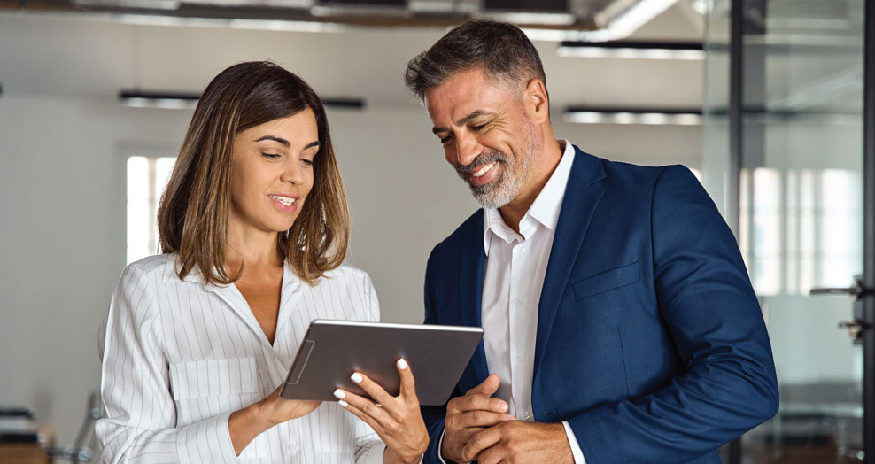 Two professionals looking at a tablet together in an office setting