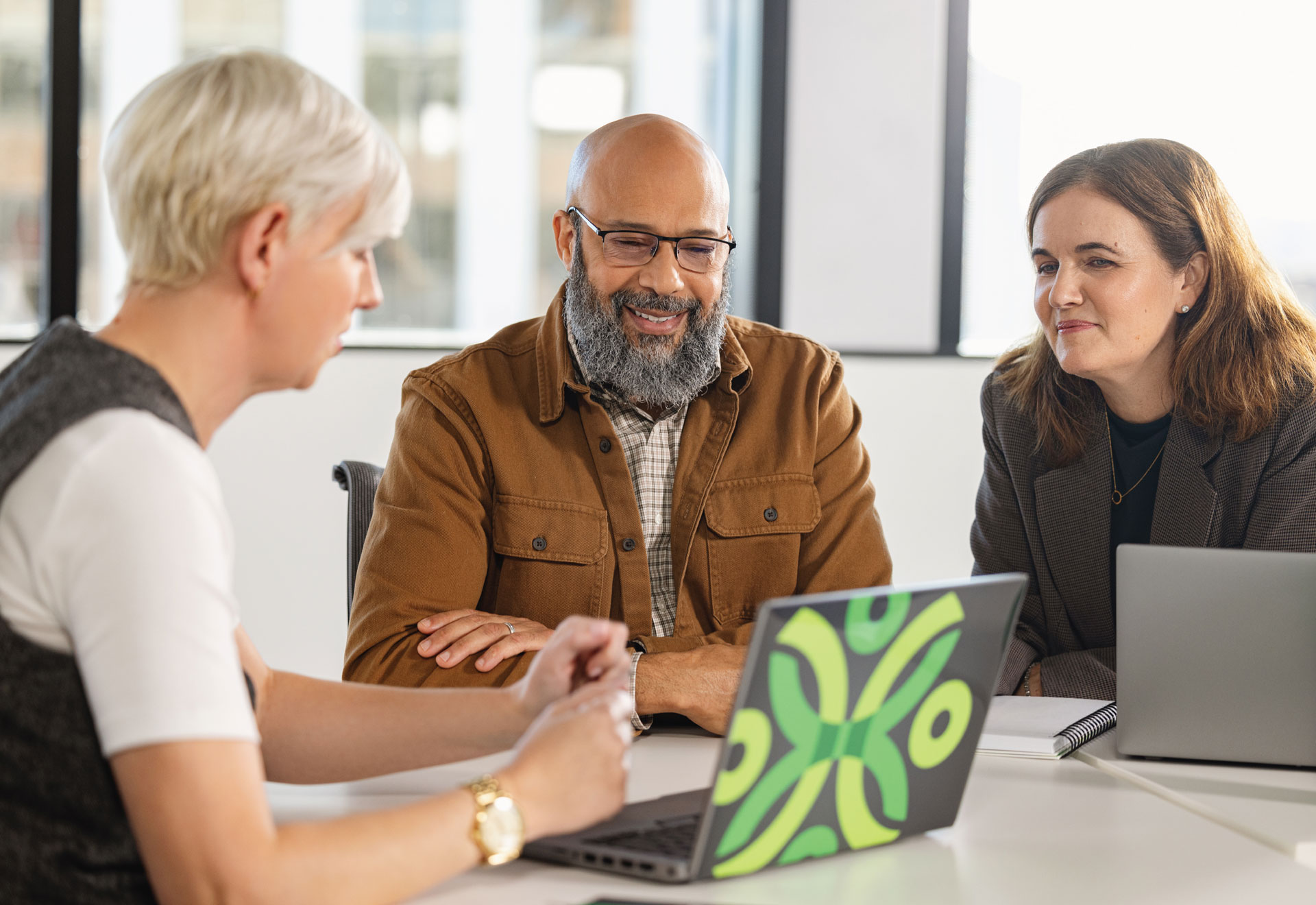 A Securian Canada representative with a Securian Canada branded laptop sits with a couple at a desk.