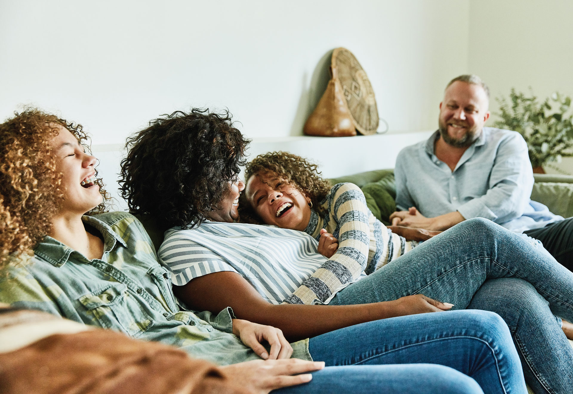 Family sitting together laughing on a green couch.