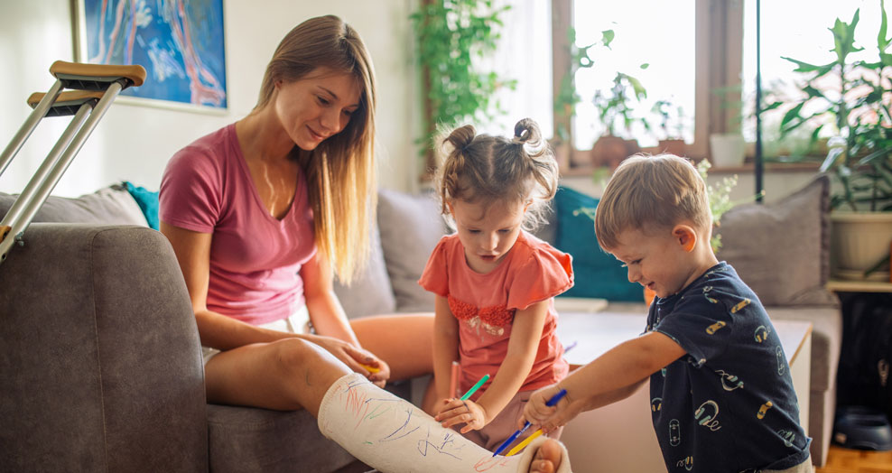 Two young children draw on a family member's cast for a broken leg.